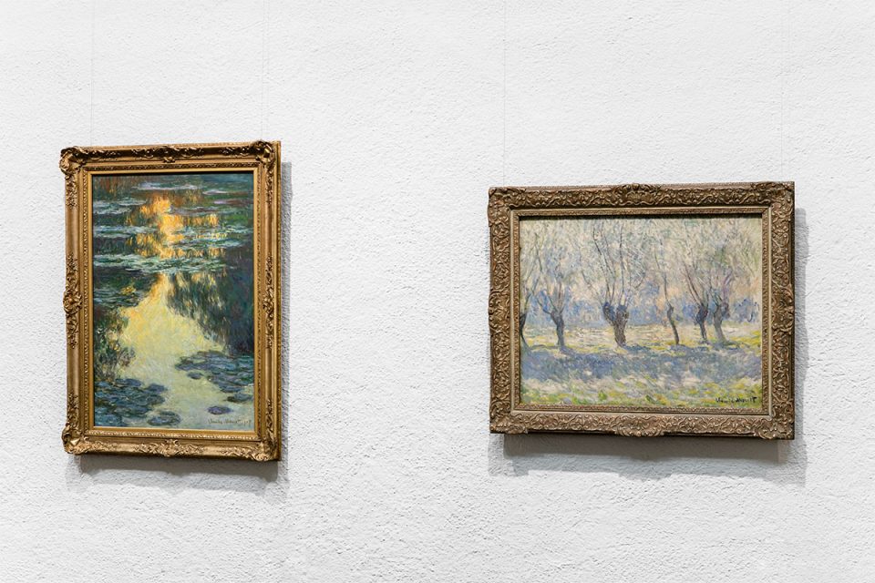 Två impressionistiska målningar av Claude Monet i guldram mot vit vägg. Till vänster: näckrosdam Till höger: pilträd på rad
