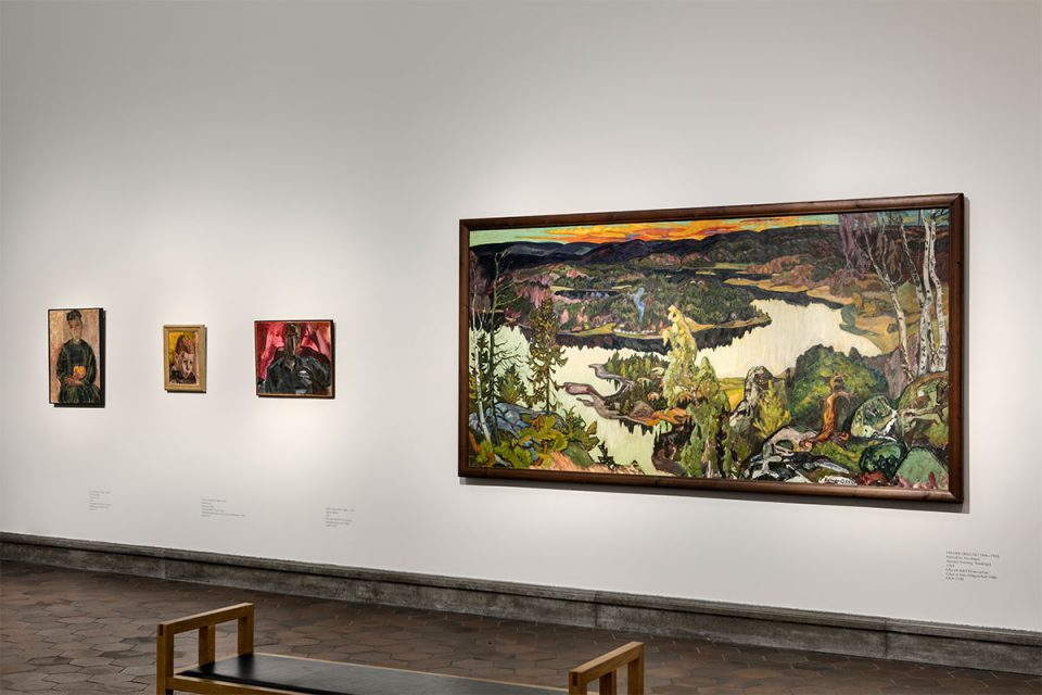 Museisal med en stor målning av landskap med träd och sjö i fågelperspektiv.